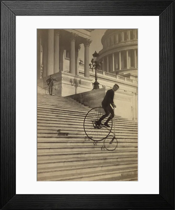 Framed Print : Man riding a penny-farthing bicycle down the Capitol steps in 1884. Another bicyclist stands further up the steps. Photo by the Platt Brothers (BSLOC_2018_2_173)