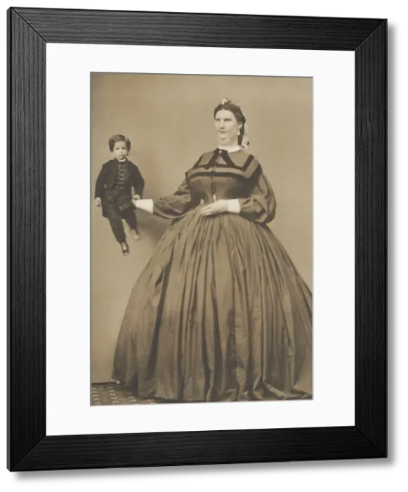 Framed Print : Anna Haining Bates, (aka Anna Swan), holding a small person in her extended hand. She was a Canadian woman famous for her great stature of 7 feet 11 inches