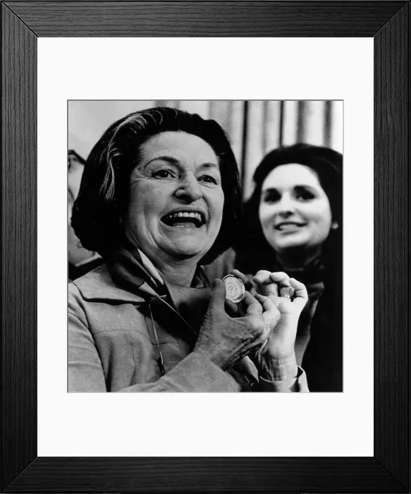 Framed Print : Lady Bird Johnson displaying an 18 karat gold medal honoring her husband, the late president Lyndon Johnson at a presentation, with daughter Lynda in the background
