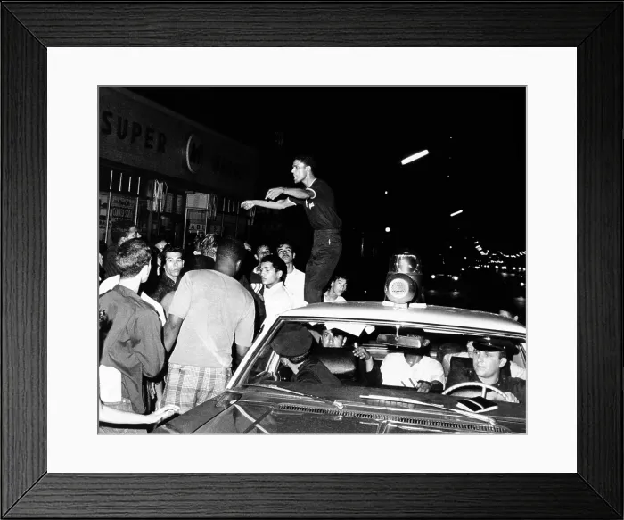 Framed Print : Puerto Rican youth standing on a police car, urges the crowd to go home and aid in dispersing neighborhood groups. Spanish Harlem, New York City, July 23, 1967