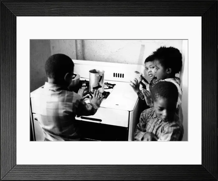 Framed Print : Four African American children cluster around the gas stove for warmth