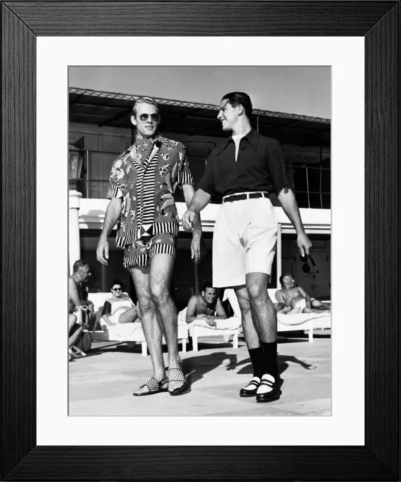 Framed Print : Men wearing the latest beach fashions. On the left, a colorful Mexican design; on the right, longer shorts and an open collar shirt. November, 1947
