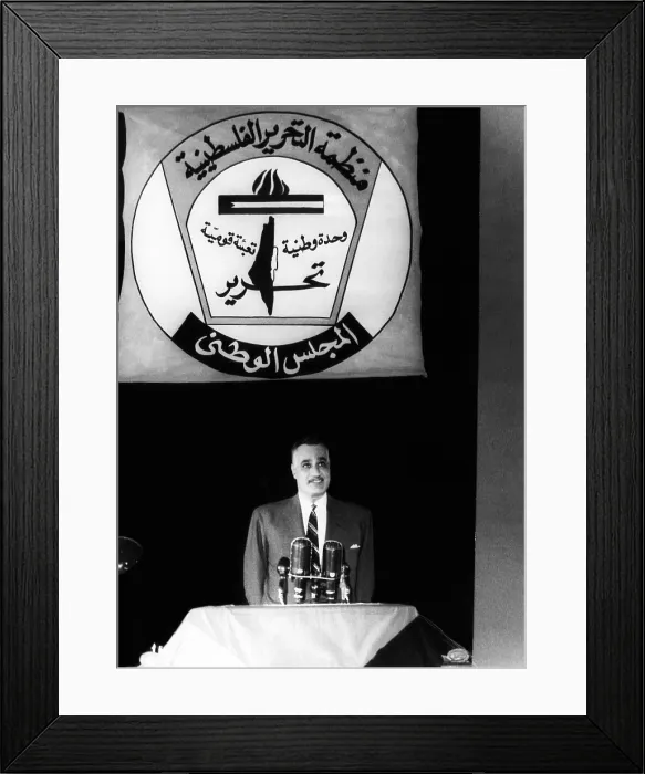 Framed Print : President of the United Arab Republic Gamal Abdel Nasser, standing under the symbol of the PLO (Palestine Liberation Organization). Cairo, Egypt, June 8, 1965