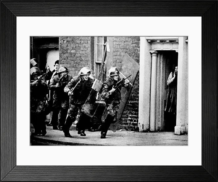 Framed Print : British soldiers chase a sniper down the street in Northern Ireland while a British housewife stands shocked in a doorway. November 21, 1973