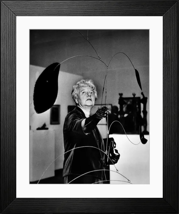 Framed Print : Peggy Guggenheim adjusts Alexander Calder's Mobile at a special exhibit of her famed collection of art at the Tate Gallery, London, England. 1965