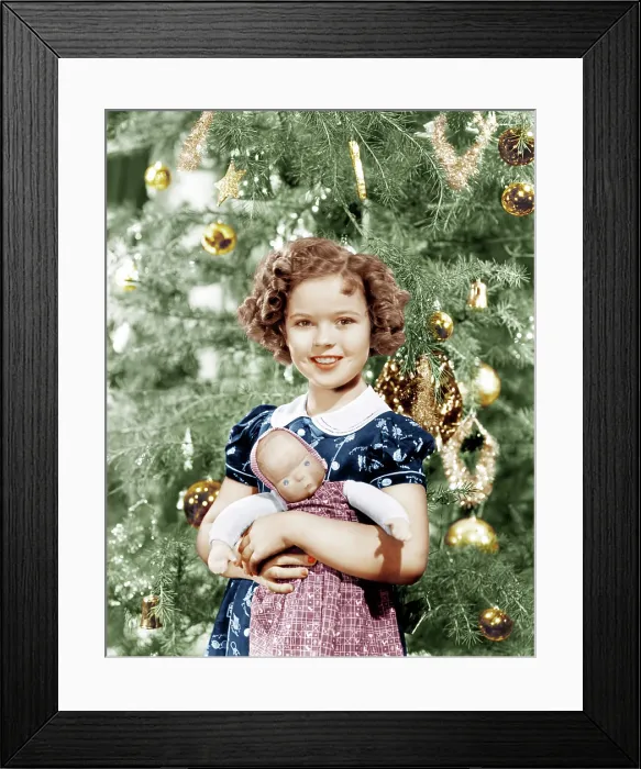 Framed Print : Shirley Temple holding doll by Christmas tree, ca. late 1930s Framed Print : Shirley Temple holding doll by Christmas tree, ca. late 1930s