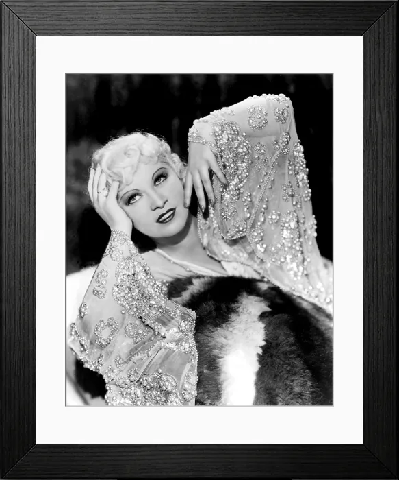 Framed Print : Mae West, in beaded dress, on fur rug, 1930s