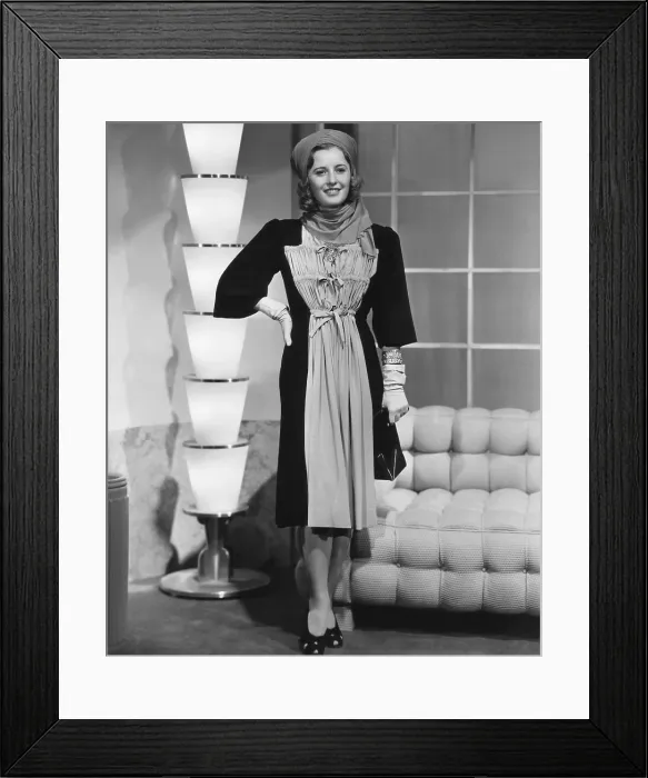 Framed Print : Barbara Stanwyck in black silk jersey and chartreuse street frock designed by Royer, 1938
