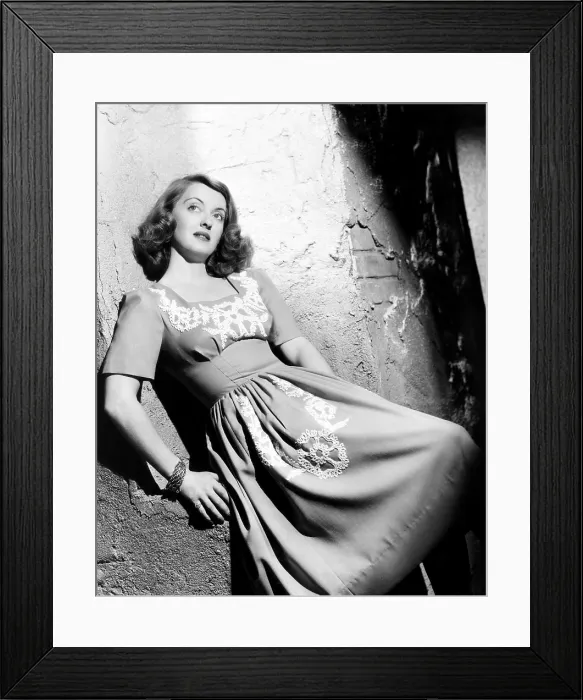 Framed Print : Bette Davis, modeling a blue linen dress with white braid details, 1940