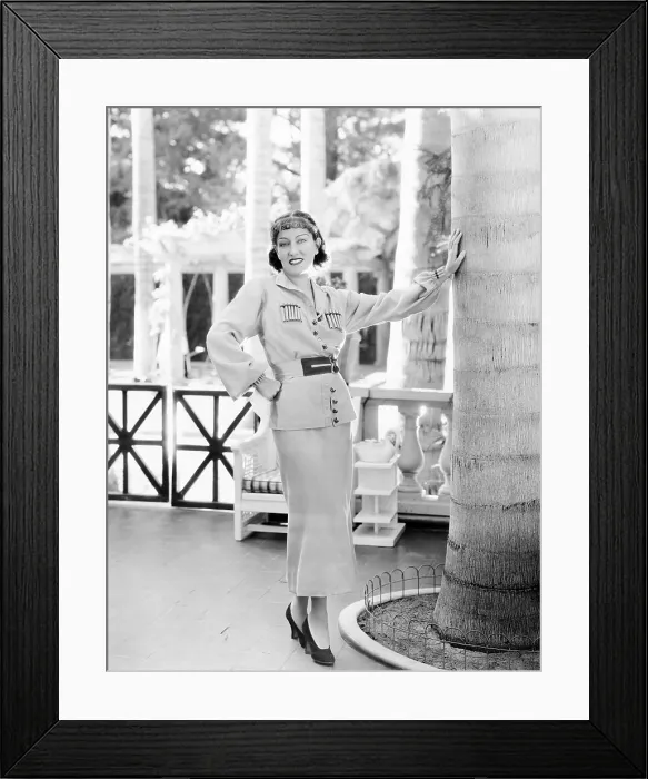 Framed Print : Gloria Swanson, modeling a gold wool sports suit with red trim, ca. 1934