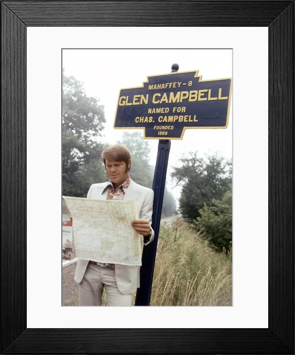 Framed Print : Glen Campbell, posing at the highway marker for the town of Glen Campbell, Pennsylvania, 1971