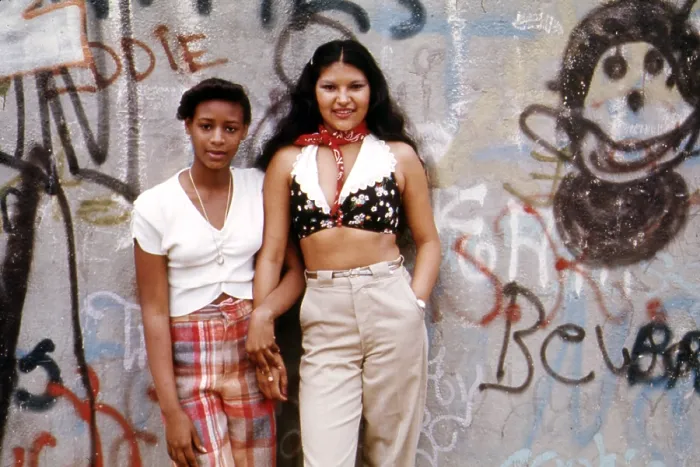 Framed Print : 1970s America. Two young girls pose in front of a graffitied wall in Brooklyn, New York City, ca. 1973