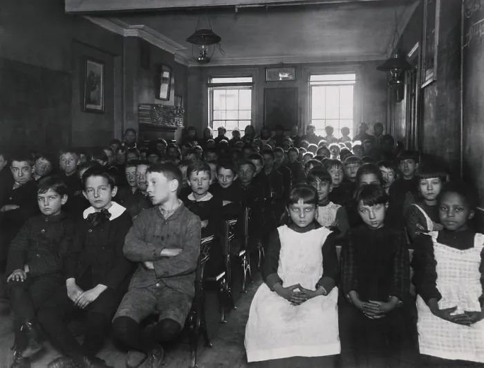 Framed Print : About 75 children packed into a NYC classroom in New York City, c. 1890. The girls are separated from boys, but all sit in chairs without desks