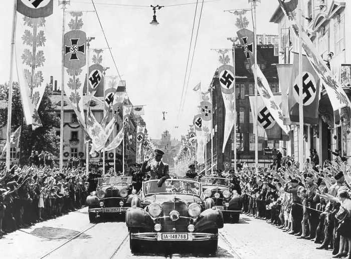 Framed Print : Adolf Hitler waving to crowds from his car at the head of a parade. The streets are decorated with various swastika banners. Ca. 1934-38. Location is unidentified Framed Print : Adolf Hitler waving to crowds from his car at the head of a parade. The streets are decorated with various swastika banners. Ca. 1934-38. Location is unidentified
