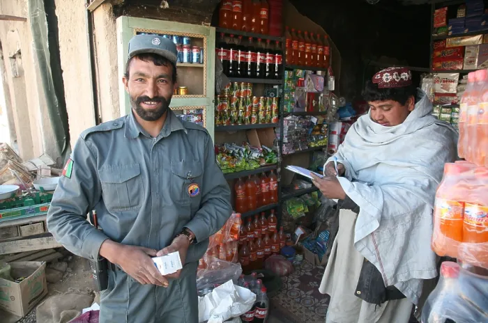 Framed Print : Afghan National Police officer shops at a store in Now Zad Helmand province Afghanistan. Residents have returned after the expulsion of the Taliban by U.S. Marines. Feb