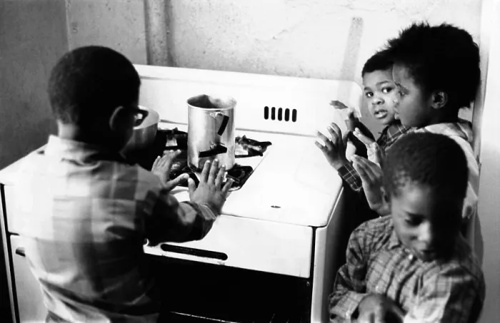 Framed Print : Four African American children cluster around the gas stove for warmth