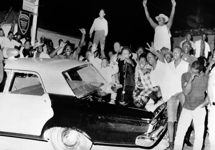 Framed Print : African American jeer police during the 1965 Watts Riots. Young men stand on a Police car on the second night of the violence protests. August 12, 1965