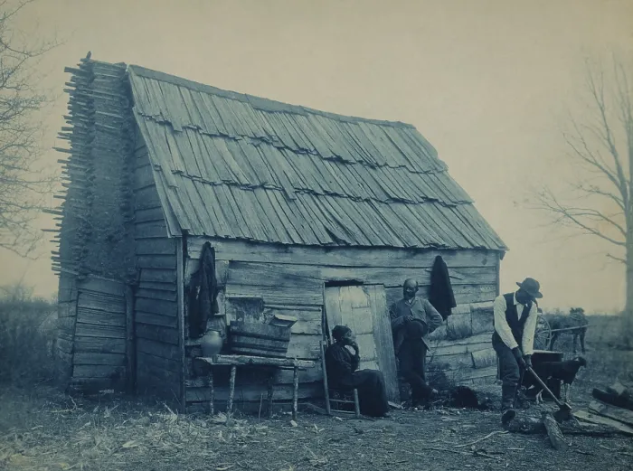Framed Print : African American man chops wood outside a cabin, presumably the home of the middle aged couple nearby. The tree is bear of leaves, and fire wood will be needed Framed Print : African American man chops wood outside a cabin, presumably the home of the middle aged couple nearby. The tree is bear of leaves, and fire wood will be needed