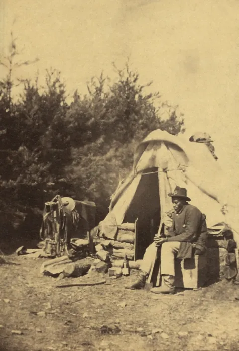 Framed Print : African American man, sitting outside a military camp tent holding an ax, during the Civil War, 1861-65. It is unclear whether he is contraband or a soldier Framed Print : African American man, sitting outside a military camp tent holding an ax, during the Civil War, 1861-65. It is unclear whether he is contraband or a soldier