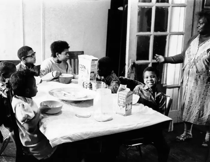Framed Print : An African American mother serves six children a breakfast of corn flakes and milk in their apartment in New York's Harlem district Framed Print : An African American mother serves six children a breakfast of corn flakes and milk in their apartment in New York's Harlem district