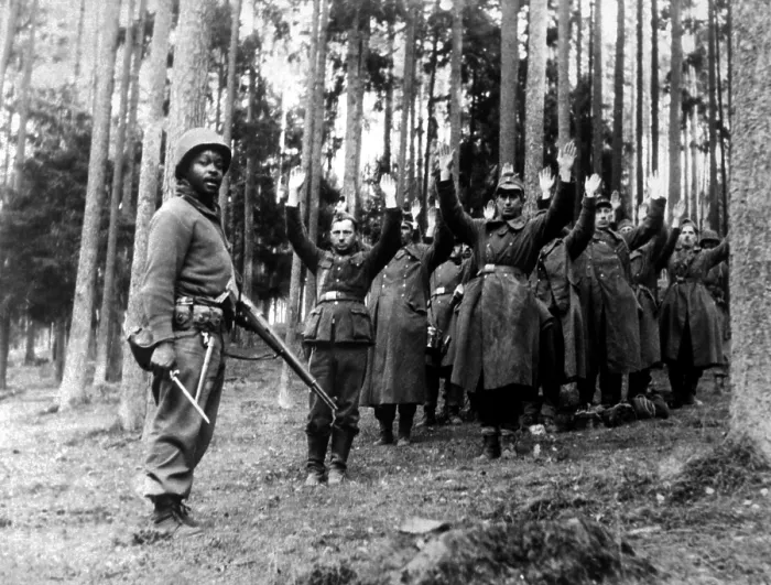 Framed Print : An African American soldier of the stands guard over a group of Nazi prisoners. The Germans were captured in the surrounding forest by the U.S Framed Print : An African American soldier of the stands guard over a group of Nazi prisoners. The Germans were captured in the surrounding forest by the U.S