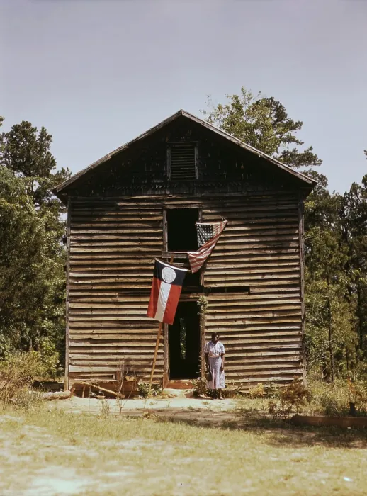 Framed Print : African American woman standing by building with Georgia state and United States flags, near White Plains, Georgia, photograph by Jack Delano, March, 1941