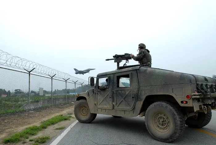 Framed Print : US Airman guards the base perimeter from the gun turret of a Humvee while an F-16 Fighter aircraft lands in the background. At Osan Air Base South Korea. July 23 2008