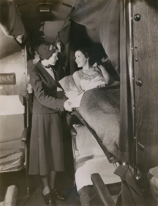 Framed Print : American Airlines stewardess with a passenger in a sleeping berth on a commercial flight in the 1930s. American Airlines began using stewardesses in 1933 Framed Print : American Airlines stewardess with a passenger in a sleeping berth on a commercial flight in the 1930s. American Airlines began using stewardesses in 1933