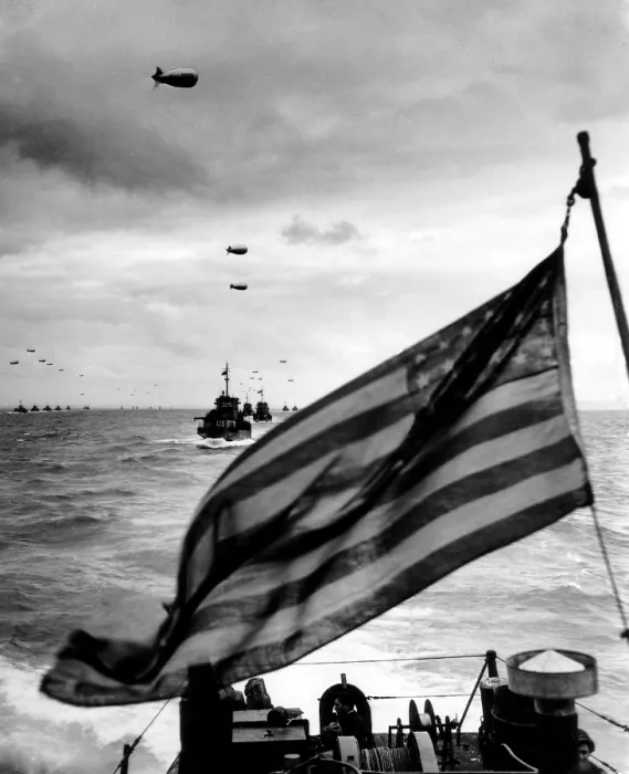 Framed Print : Behind an American flag, a convoy of landing craft head for Utah Beach on June 6, 1944