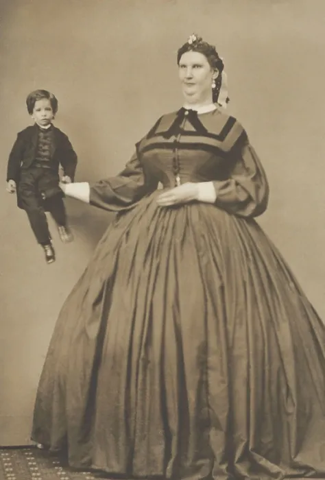 Framed Print : Anna Haining Bates, (aka Anna Swan), holding a small person in her extended hand. She was a Canadian woman famous for her great stature of 7 feet 11 inches