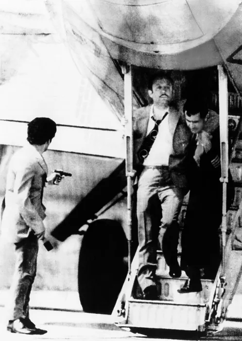 Framed Print : An armed hijacker (left) watches as Turkish Airlines crew member employee assists a passenger who suffered a heart attack on the air liner at Sofia, Bulgaria