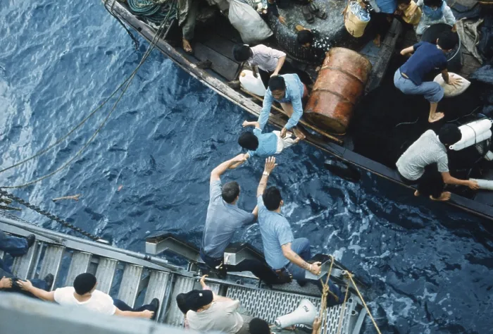 Framed Print : Assistance to Boat People, in a small craft on South China Sea, April 3, 1975. Crewmen of the amphibious cargo ship USS Durham take on Vietnamese refugees
