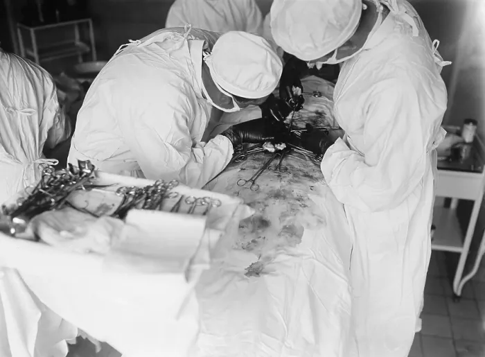 Framed Print : Attending surgeon leans over to work closely over a patient's abdomen. The surgical field is stained with blood. 1922 in a hospital in Washington, D.C. (BSLOC_2016_10_36) Framed Print : Attending surgeon leans over to work closely over a patient's abdomen. The surgical field is stained with blood. 1922 in a hospital in Washington, D.C. (BSLOC_2016_10_36)