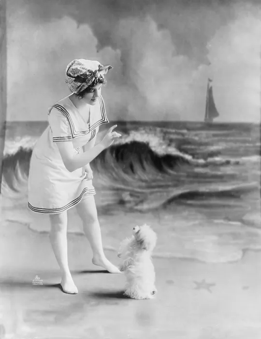Framed Print : Bathing beauty, young woman in bathing suit with small dog in front of studio backdrop of beach, photograph, 1913 Framed Print : Bathing beauty, young woman in bathing suit with small dog in front of studio backdrop of beach, photograph, 1913