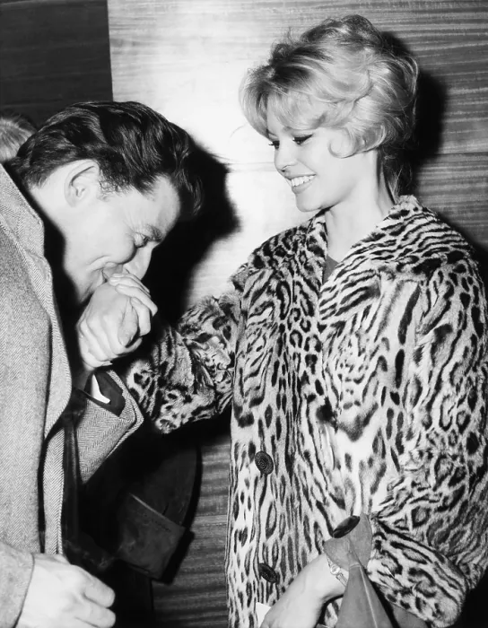 Framed Print : Brigitte Bardot receives an old-fashioned style kiss from actor Gerald Philippe. They were attending the premiere of the movie Montparnasse 19 in Paris