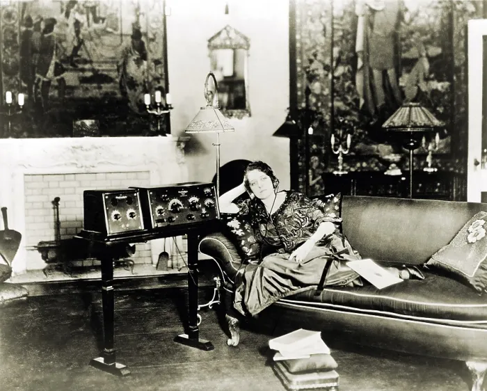 Framed Print : Broadcast radio's first decade prompted novel uses. Photo shows a shut-in woman, wearing radio headset, listening to radio on stand next to sofa. 1923