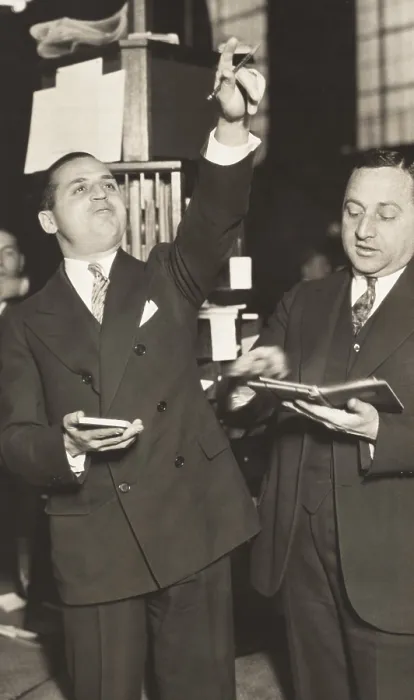 Framed Print : Two brokers at New York Curb Exchange Building in 1929. One is signaling with his hands as another leafs through a notebook