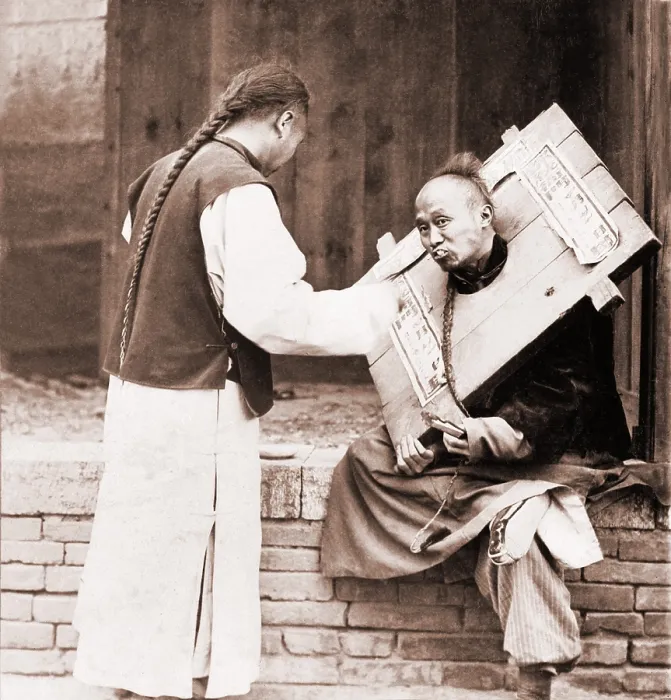 Framed Print : Charitable Chinese man feeding a criminal in a cangue. Petty criminals were sentenced to wear the canque, often for a couple of months, and display themselves in public places