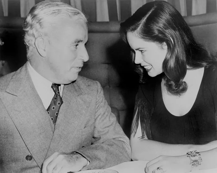 Framed Print : Charlie Chaplin (1889-1977) sitting with his young wife Oona at Hollywood nightclub in 1944. The couple married the previous year, when Oona was 18 and Charlie was 54