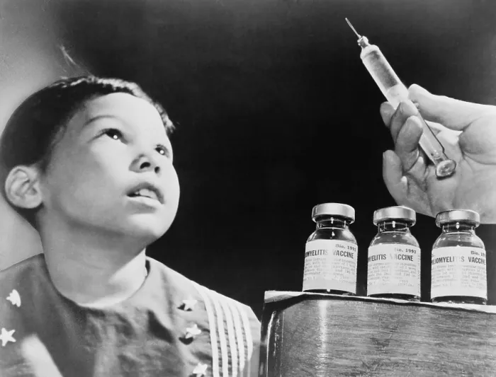 Framed Print : Child looks at a syringe with poliomyelitis vaccine. The Salk Vaccine, developed in 1955, was distributed worldwide and to prevent Polio