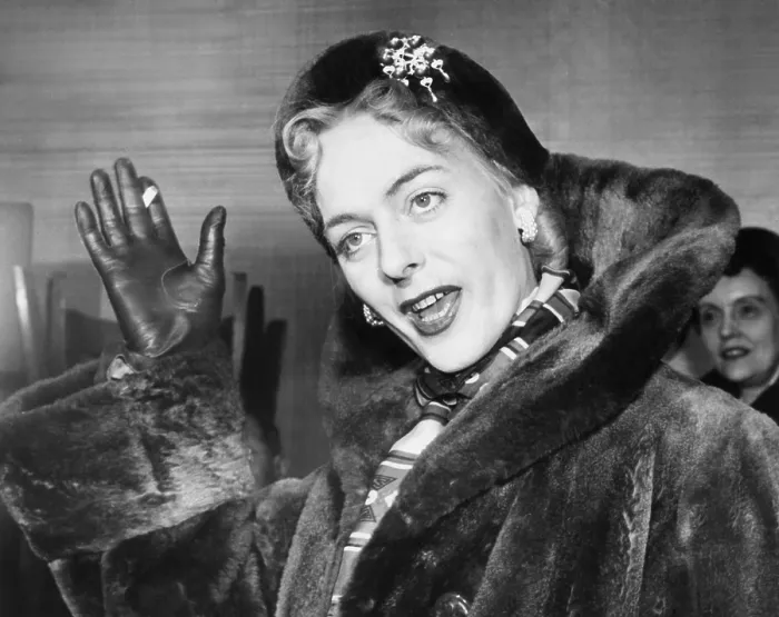 Framed Print : Christine Jorgensen, waves to photographers, upon her arrival at Idlewild from Denmark. Feb. 12, 1953