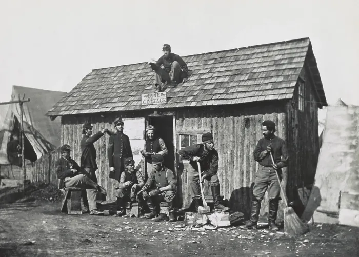 Framed Print : US Civil War, 1863. Pine Cottage, a hut built in Union soldiers winter quarters. Nine men, pose sitting or doing some work