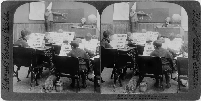 Framed Print : Classroom with children reading various crime stories and boy, wearing dunce cap, at blackboard, original title: But, Oh! see what they are studying