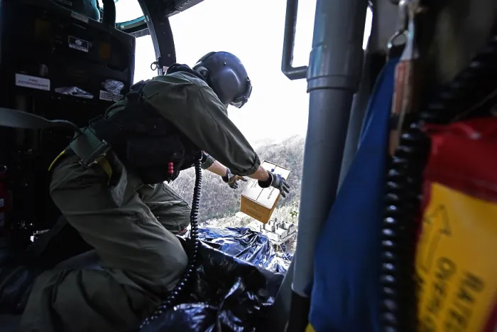 Framed Print : US Coast Guard helicopter drops a box of MRE's to locals near Utuado, Puerto Rico. The community was stranded after Hurricane Maria by washed out roads and mudslides, Oct