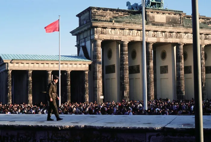 Framed Print : Crowds of Berliners around the Brandenburg Gate following the structure's official opening on Dec. 22 1989. In the foreground an East German guard walks on the Berlin Wall