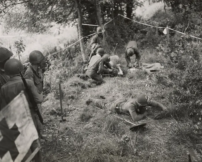 Framed Print : Doctors and medics giving first aid to a combat engineer injured by a land mine. At lower right, a soldier sweeps the area for mines. June-Aug. 1944