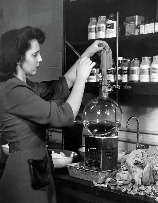 Framed Print : DuPONT COMPANY LABORATORY-- Woman starting a pair of used nylons through a process developed at the laboratory which chemically unravels the stockings all the way back to their
