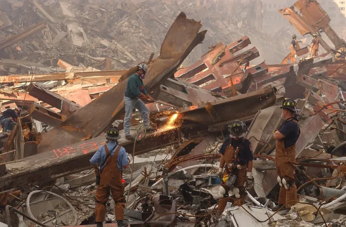 Framed Print : Dwarfed by the debris from the World Trade Center metal workers cut though the rubble pile in a futile search for survivors a week after the attacks, September 19, 2001