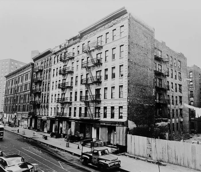 Framed Print : East Harlem street and large tenement apartment building at 311 East 100th Street in New York City. 1964