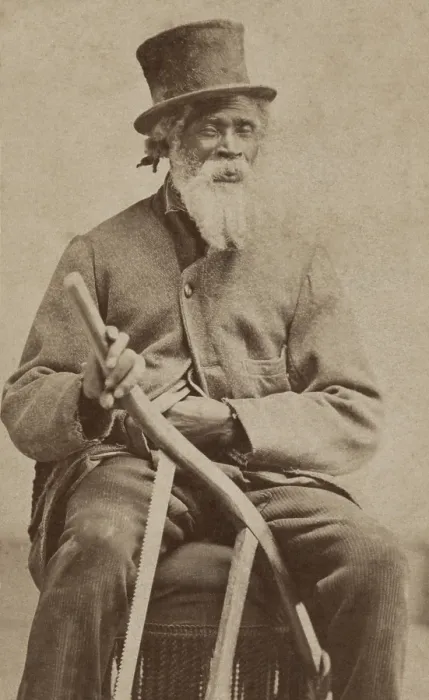 Framed Print : Elderly African American man poses with a top hat, coat, and with a bow saw, c. 1855-1870. The bow saw suggests he was a valuable and skilled carpenter